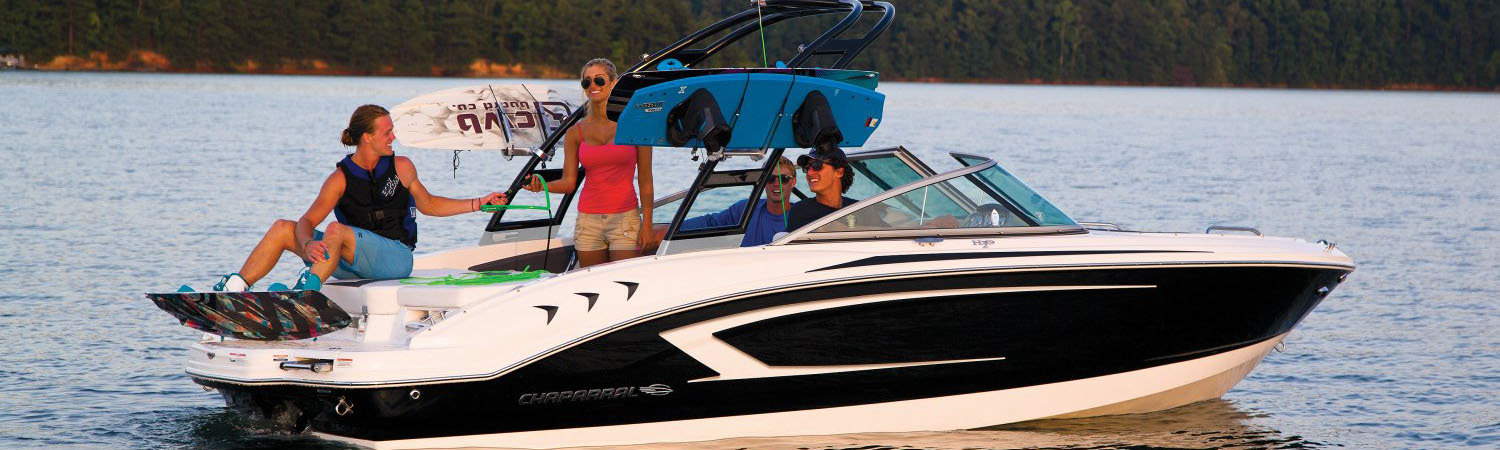 Four friends on a boat with a man putting getting ready to wakeboard off the back of the boat.